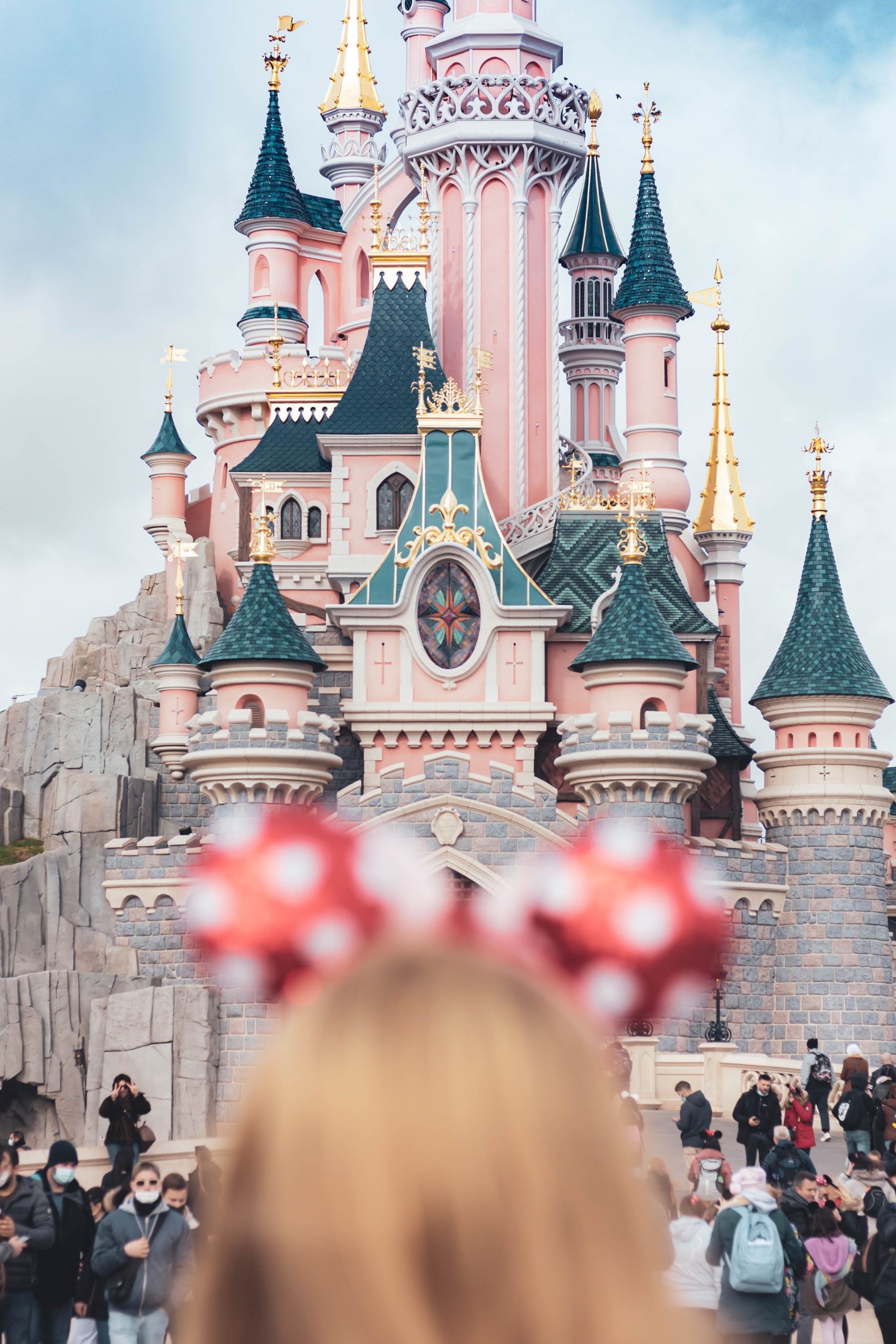 Family arriving at Marne-la-Vallée–Chessy station with luggage, Disneyland Paris entrance in the background